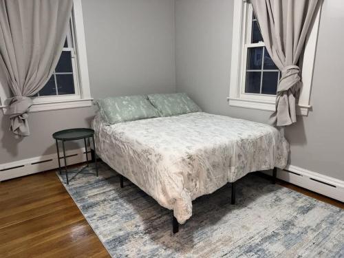a bedroom with a bed and two windows at Comfortable 4 Bed Home close to Gillette in Foxborough