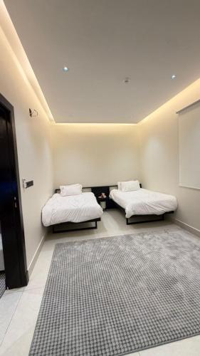 two beds in a room with a rug at نُزل البدر - غرفة و صالة دخول ذاتي in Al Kharj