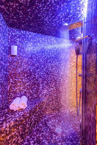 a bathroom with a shower with two towels on a tile wall at Dharma Luxury Hotel in Rome