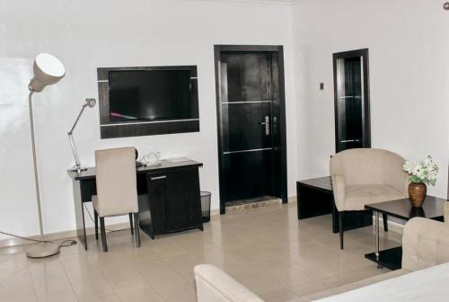 a living room with a television and a desk and chairs at ModexD'Crib in Lagos