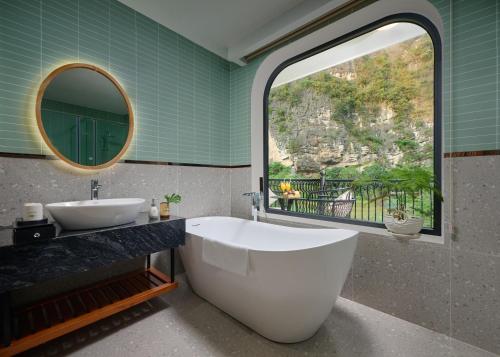 a bathroom with a tub and a sink and a window at Heritage Charm Hotel Trang An in Ninh Binh