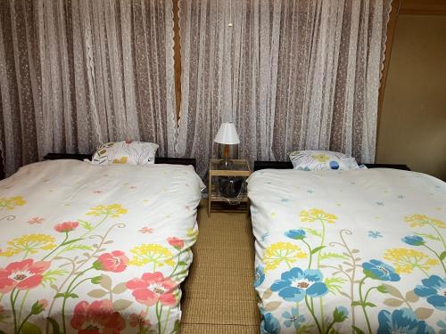 a bedroom with two beds with flowers on them at 一棟貸ひなたぼっこくらなみ in Nagano