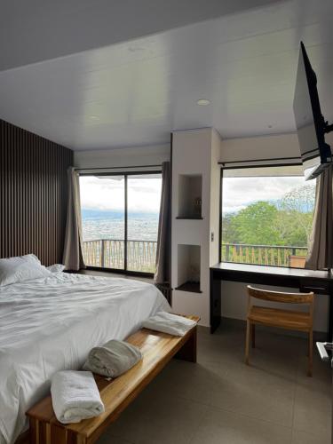 a bedroom with a large bed and large windows at Villas Amíwa in Alajuelita