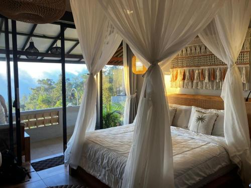 a bedroom with a canopy bed with a large window at Munduk Pondok Canopee in Ambengan