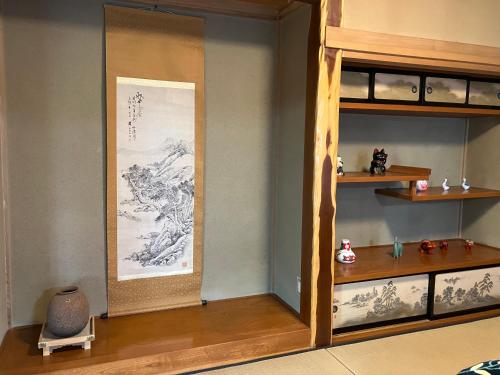a room with a wall with a painting and a shelf at 一棟貸ひなたぼっこくらなみ in Nagano