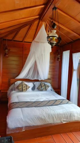 a bedroom with a bed with curtains and a chandelier at Tentrem Bungalow in Labuan Bajo