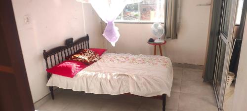 a bedroom with a bed with red pillows and a window at Casa branca in Aracaju