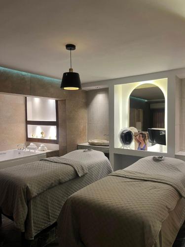 Eine Frau fotografiert ein Badezimmer mit zwei Betten in der Unterkunft Platinum Hôtel Spa Abidjan Cocody in Abidjan
