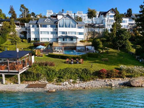 a group of people sitting on the grass near the water at Sol del Nahuel - Hotel Boutique & Spa in San Carlos de Bariloche