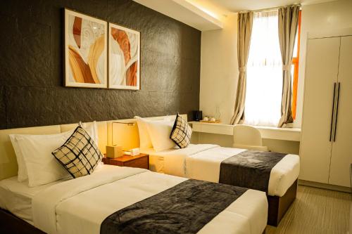 ein Hotelzimmer mit zwei Betten und einem Fenster in der Unterkunft Madayaw Hotel Tagum in Tagum