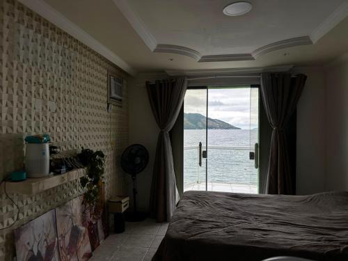 a bedroom with a bed and a view of the ocean at Meneghetti Mangaratiba in Mangaratiba