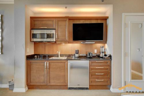 a kitchen with a sink and a microwave and a tv at Deluxe Spa 24th floor Signature Studio with Mountain View in Las Vegas