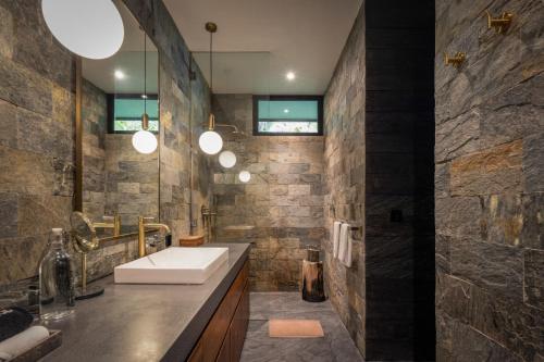 a bathroom with a sink and a stone wall at Munduk Cabins in Munduk
