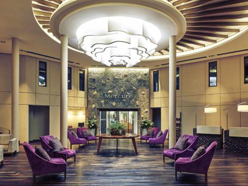 a lobby with purple chairs and a table and a chandelier at Mercure Iguazu Hotel Iru in Puerto Iguazú