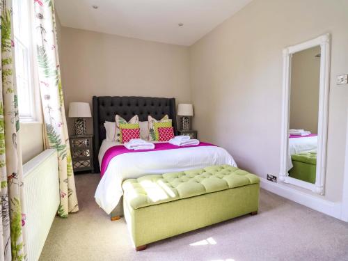 a bedroom with a bed with a green ottoman and a mirror at South Tower Cottage in Macclesfield