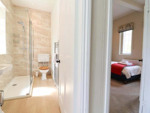 a bathroom with a shower toilet and a bed at South Tower Cottage in Macclesfield
