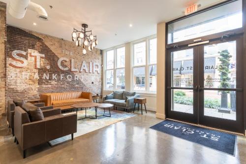 a lobby with couches and chairs in front of a brick wall at The Saint Clair in Frankfort