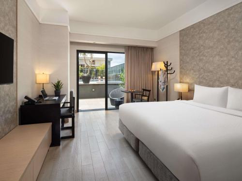 a hotel room with a large bed and a desk and a desk at Grand Mercure Singapore Roxy in Singapore