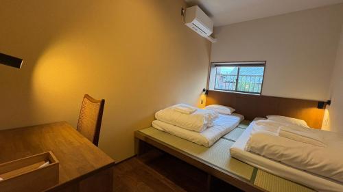 a room with two beds and a table and a window at New open - ねどことあさげナマケモノ Nedoko & Asage by Sloth - Japanese Traditional House in Ōno
