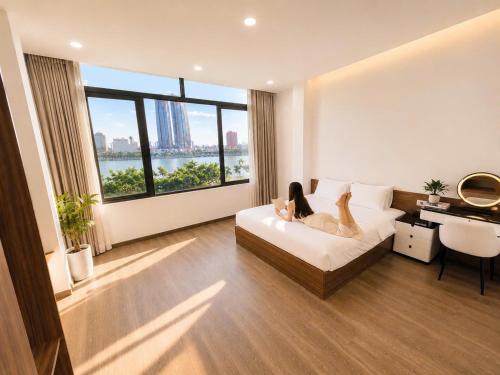a woman laying on a bed in a room with a window at Min Sweet Home 2 in Danang