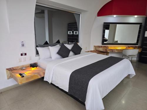 a bedroom with a large white bed and a mirror at Hotel Alcampo in Querétaro