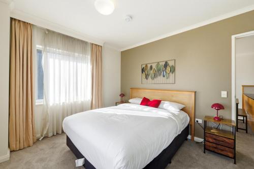 a bedroom with a large white bed with red pillows at Stylish 2-Bed Stay with Pool & Parking in Canberra