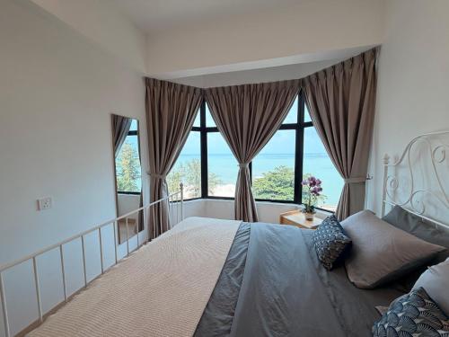 a bedroom with a large bed and large windows at SEAVIEW - BEACHFRONT - 2BR Apartment - Corner Unit- Mutiara Melaka Beach Resort Pantai Puteri in Malacca