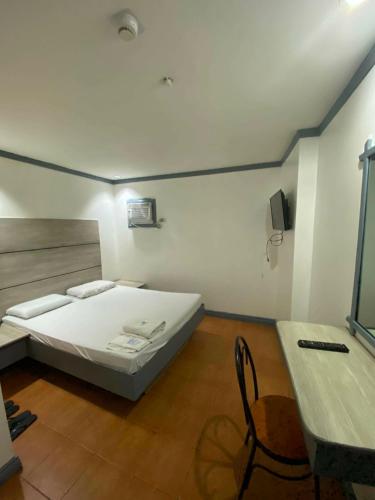 a bedroom with a bed and a table and a chair at Nice Hotel Arayat Cubao in Manila