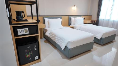 a hotel room with two beds and a tv at Casa Mysa Hotel Kuta in Kuta