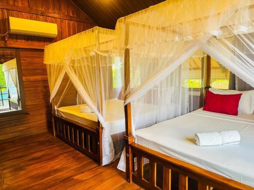 two beds in a room with wood flooring at Chaya Villa Sigiriya in Sigiriya