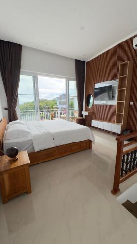 a bedroom with a large bed and a large window at Rdm Bali Guest House in Badung