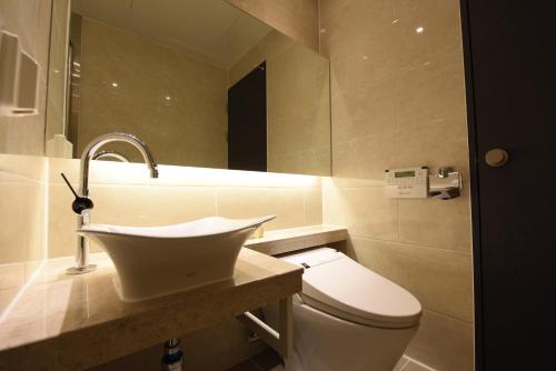 a bathroom with a sink and a toilet at Geoje Artnouveau Suite Hotel in Geoje 