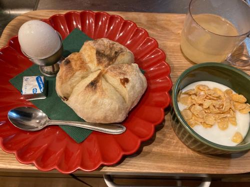 a plate with bread and a bowl of milk and a spoon at Guesthouse LuLuLu 無料朝食&夕食ｶﾚｰ付き ﾛｰｿﾝ隣 街まで電車8分 in Kochi