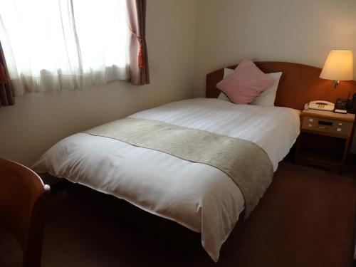 1 dormitorio con 1 cama blanca y ventana en Hotel Hashimotorou, en Ishioka
