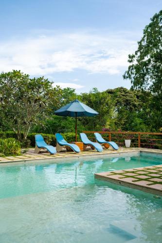 a group of chairs and an umbrella next to a swimming pool at Rukgala Retreat in Digana