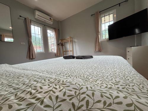 a large white bed in a room with windows at Mango Guest House Choeng Thale in Ban Thalat Choeng Thale