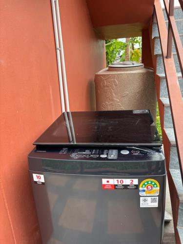 a washing machine sitting next to a wall at Mango Guest House Choeng Thale in Ban Thalat Choeng Thale