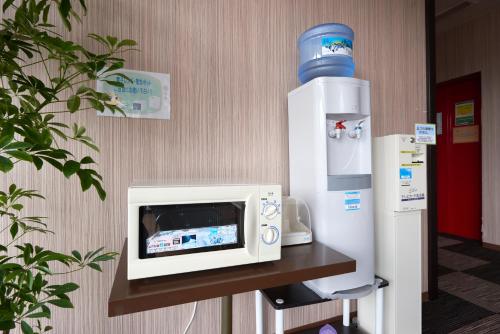 un forno a microonde su una mensola accanto a un distributore d'acqua di Select Inn Shimada Ekimae a Shimada
