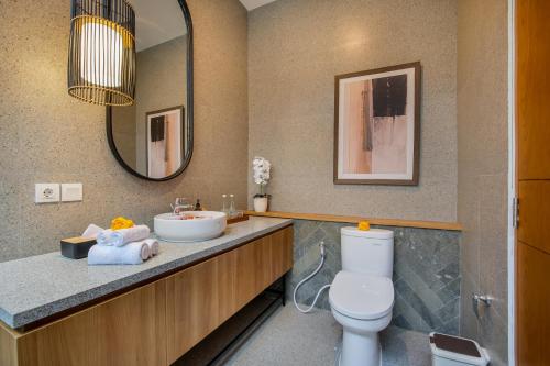 a bathroom with a sink and a toilet and a mirror at Ellavie Villa Ubud in Ubud