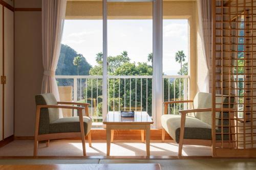 a living room with a table and chairs and a large window at Hotel Tokinoza in Kihokucho