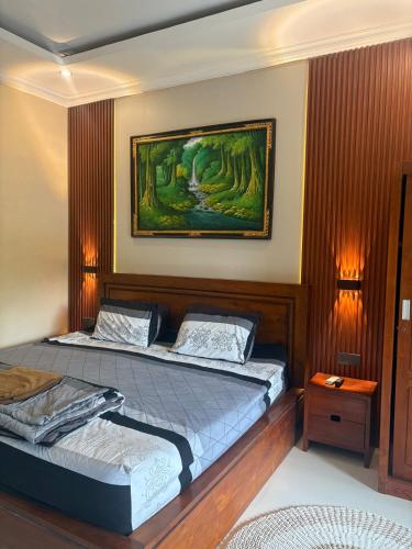a bedroom with two beds and a painting on the wall at Dede House 1 Private Pool in Ubud