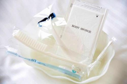 a plastic container with a toothbrush and a happy shower sign at Art Hotel Joetsu in Joetsu