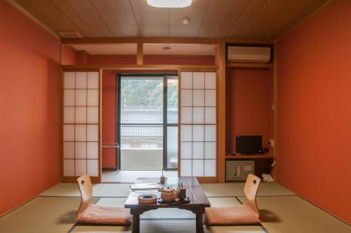 a room with orange walls and a table and chairs at 湖上館パムコ in Wakasa