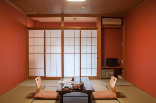 a room with a table and chairs and a large window at 湖上館パムコ in Wakasa