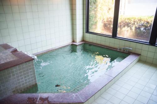 a bathroom with a tub with water in it at 湖上館パムコ in Wakasa