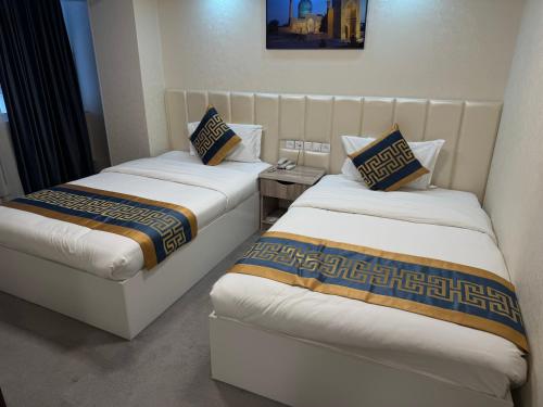 two beds sitting next to each other in a room at Sayohat Hotel in Tashkent