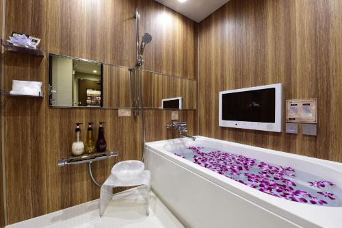 a bathroom with a tub covered in purple petals at Hotel Bali An Resort Shinsaibashi in Osaka