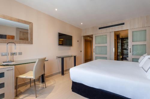 a bedroom with a large white bed and a desk at Meliá Sevilla in Seville