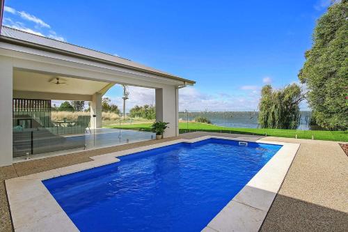 a blue swimming pool in front of a house at Woodbine Waters Lakehouse in Yarrawonga