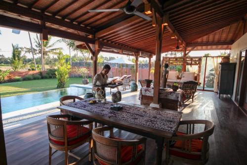 a man standing at a table in a pavilion at Villa Taman Kanti in Ubud